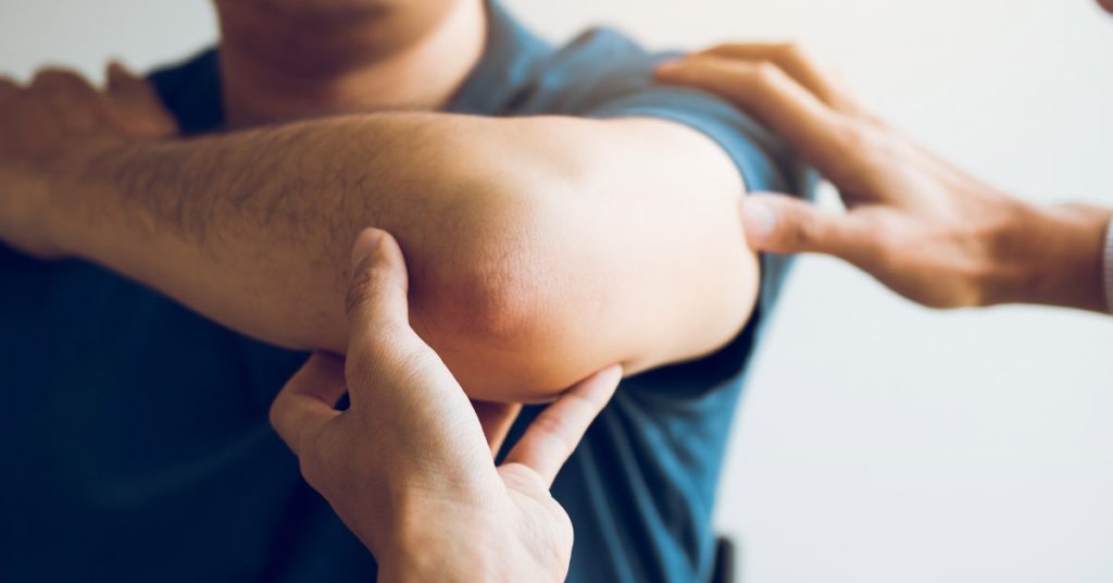 Therapist examining a man's elbow.